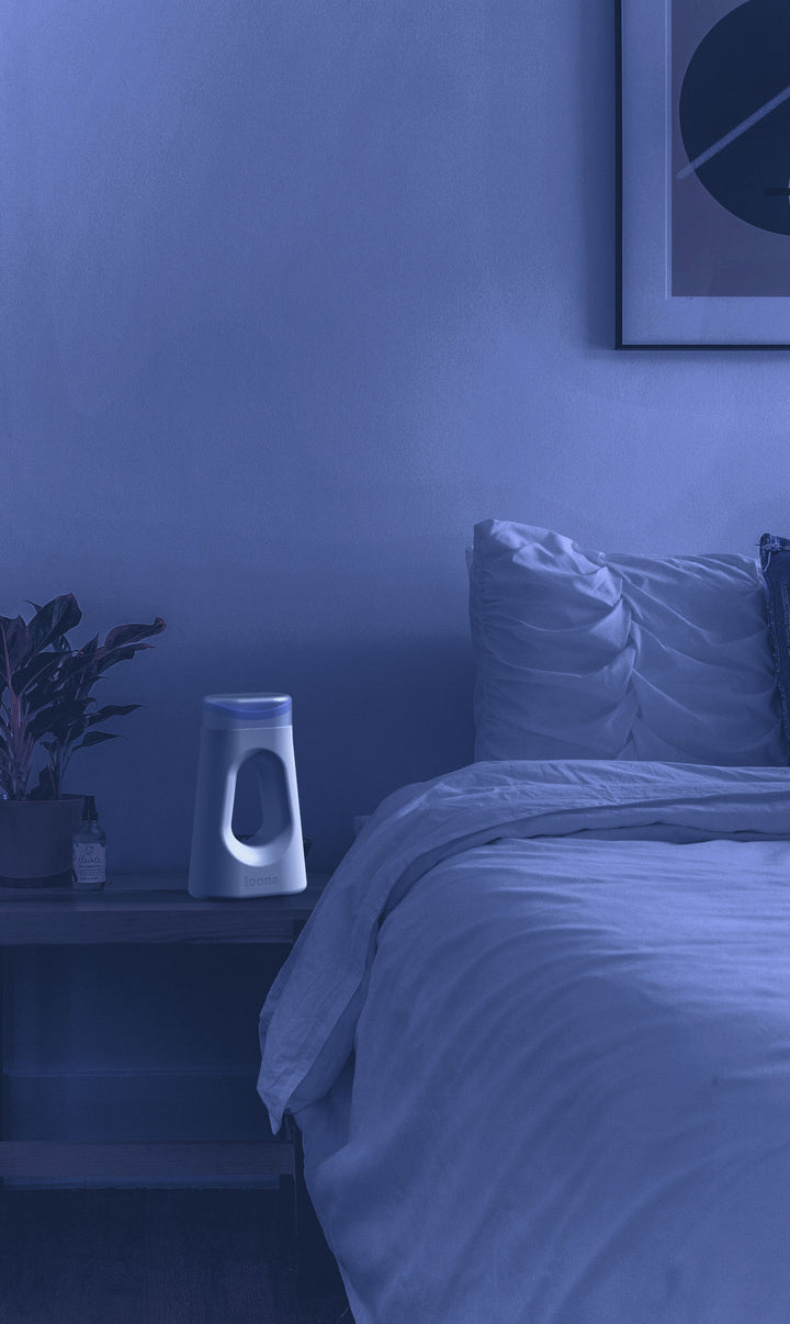 This image shows a bed at night with the Loona Female Urinal on the nightstand.