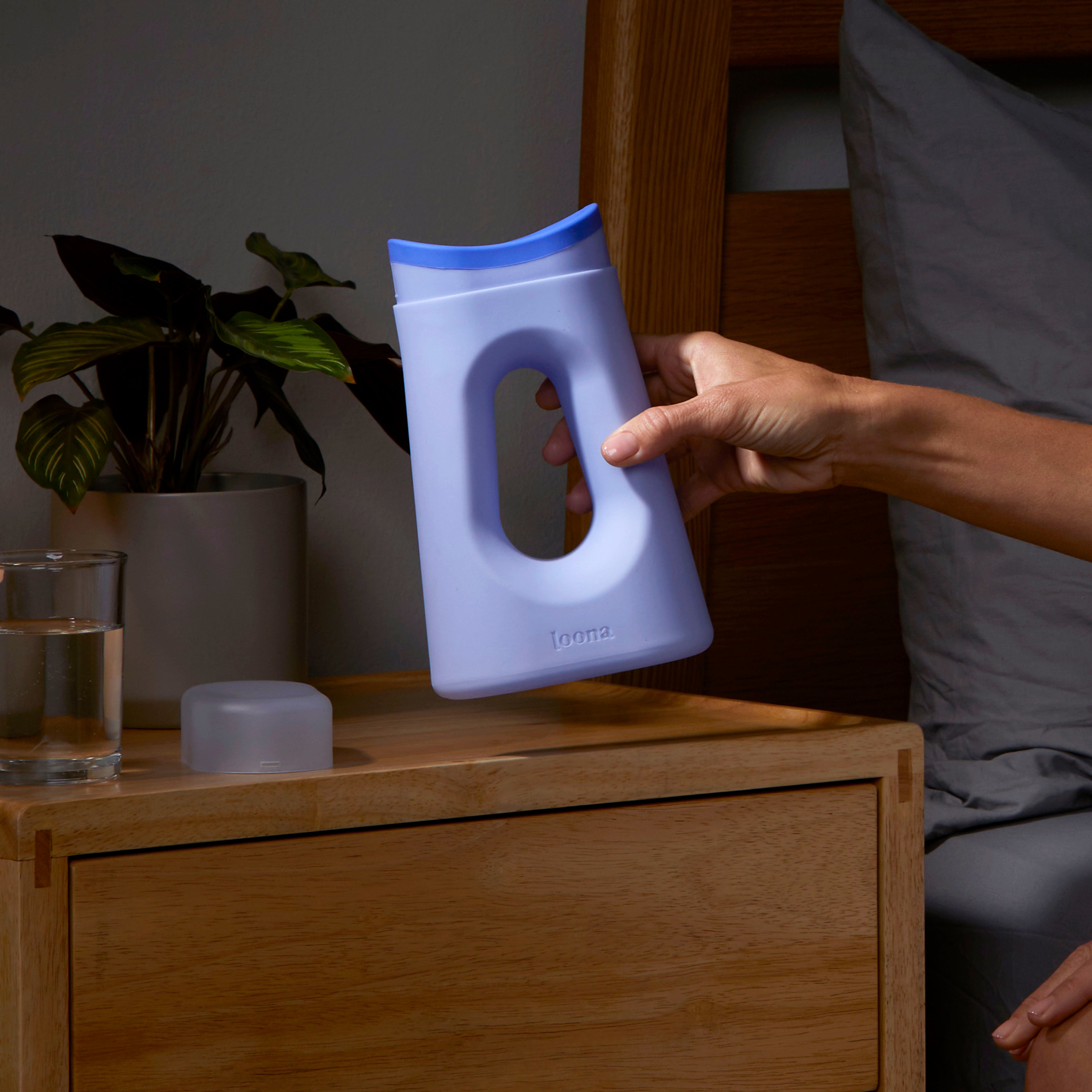 A woman's hand enters frame from the right an holds the Loona Female Urinal up to the camera demonstrating how easy it is to hold the comfortable handle. A woman's hand enters frame from the right an holds the Loona Female Urinal up to the camera demonstrating how easy it is to hold the comfortable handle.